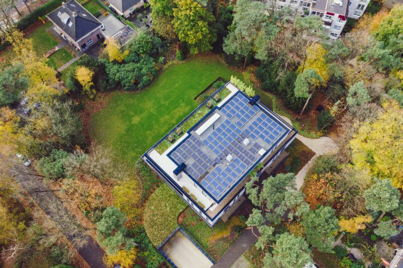 Bovenaanzicht: luchtfoto van bovenkant moderne appartementenvilla met bosrijke omgeving en zonnepanelen in Den Dolder