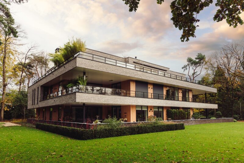 Zijaanzicht van appartementenvilla met bosrijke omgeving in Den Dolder