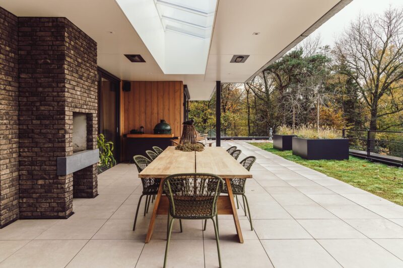 Zijaanzicht van appartementenvilla met bosrijke omgeving & tuinontwerp met overkapping in Den Dolder