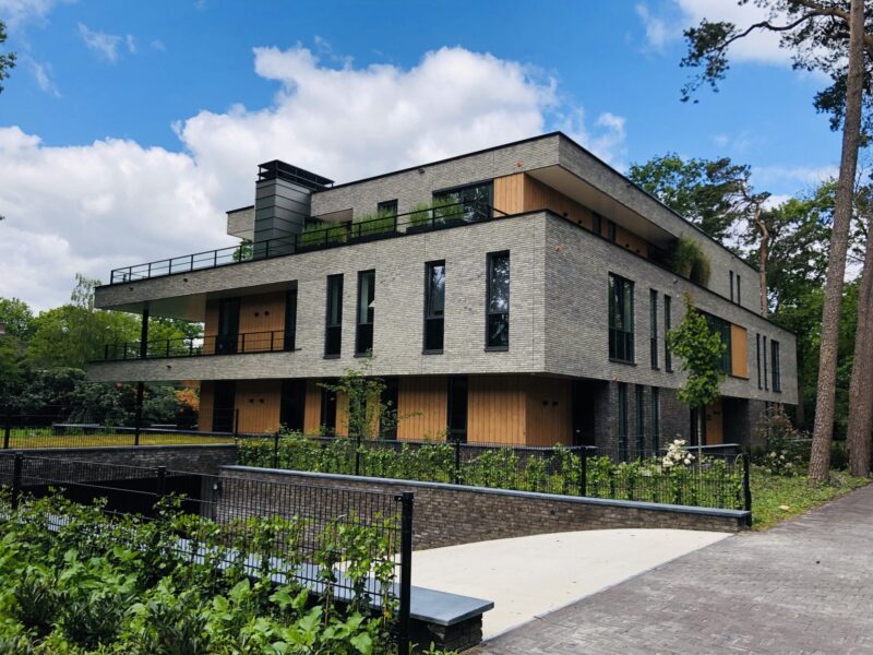 Zijaanzicht van moderne appartementenvilla met bosrijke omgeving in Den Dolder