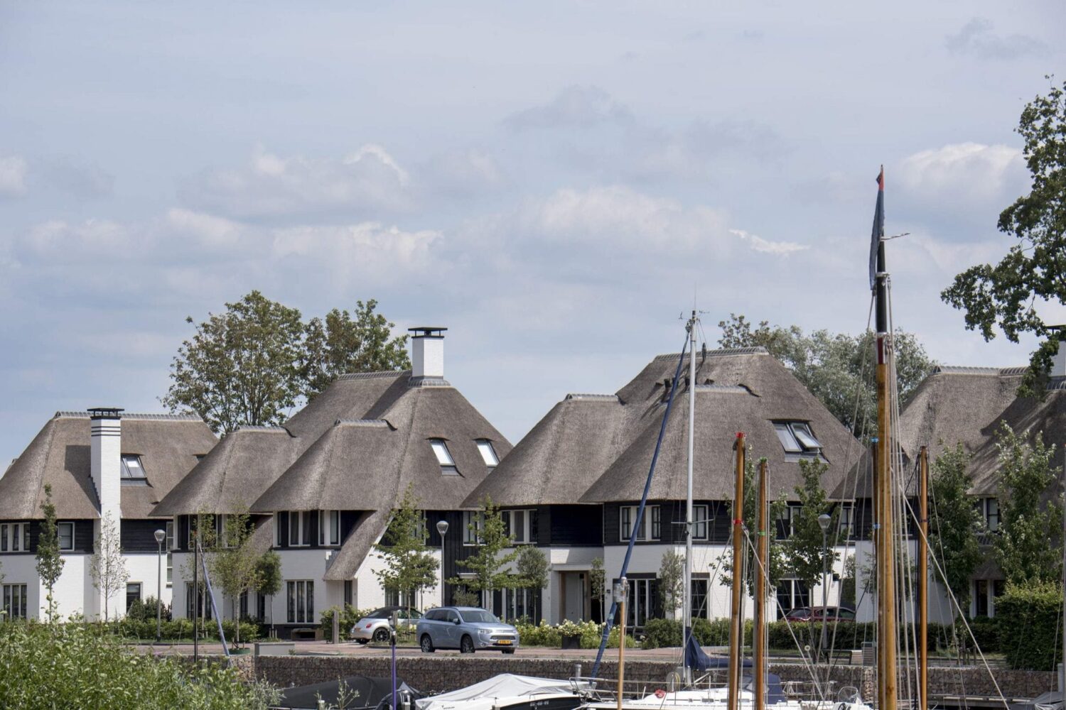 Shot van de haven en woningen met rieten dak op Naardereiland te Naarden