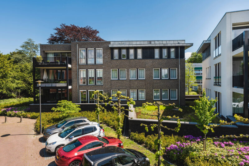 Zijaanzicht met parkeerplaatsen van appartementen in het centrum: Larens Hart